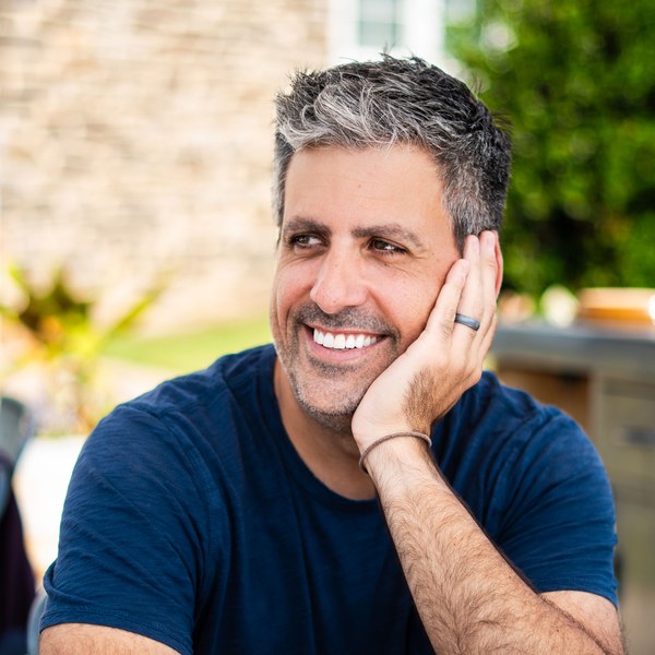 Brody Bond seated outdoors, chin in hand, laughing mid-conversation