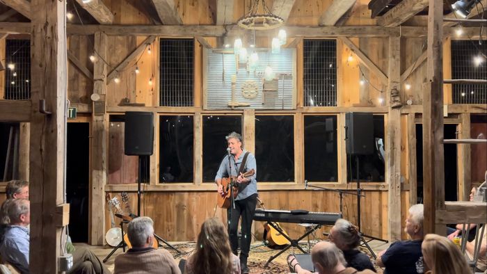 A barn hung with string lights, guitar and piano on the floor, the audience close in